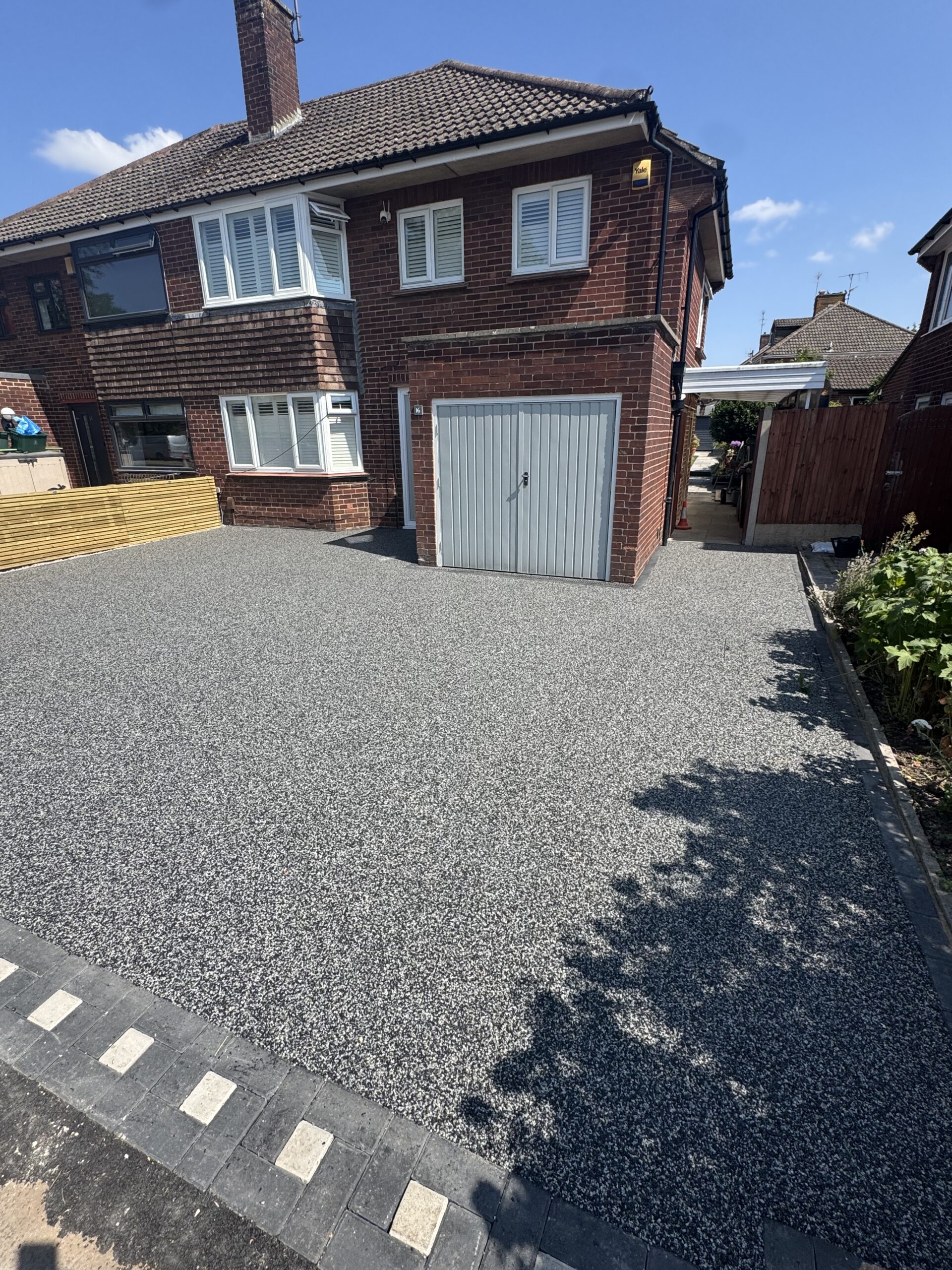 charcoal grey resin driveway with patterned block paving border in winchcombe